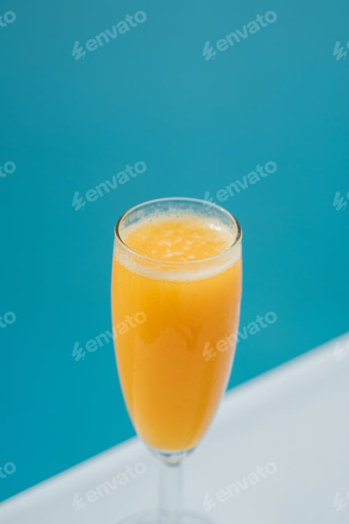 Preview: Vertical view of a glass of orange juice before the blue background
