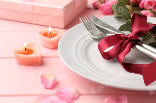 Preview: Place setting with roses and candles on pink table, closeup. Romantic dinner
