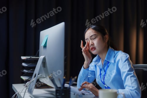 Preview: Woman rubbing tired eyes working late night in office