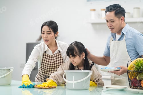 Preview: Asian young family teaching their daughter to clean kitchen counter.