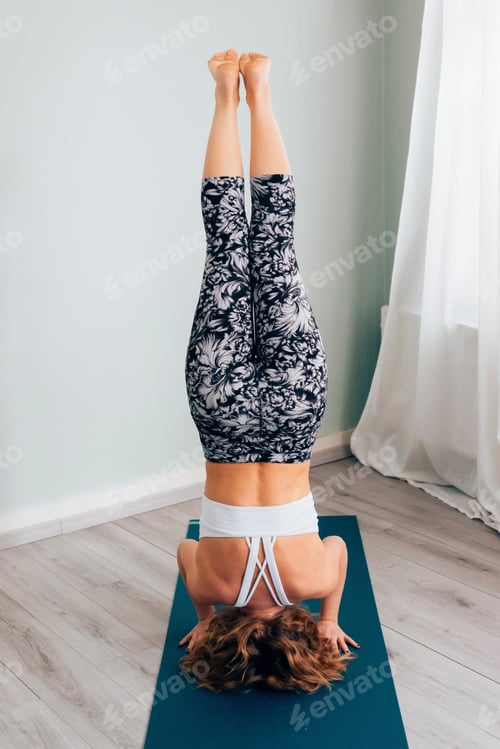 Preview: woman doing handstand position on yoga mat - salamba sirsasana pose