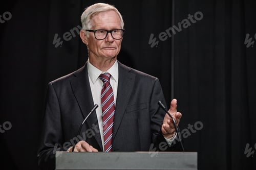 Preview: Senior Male Politician Explaining New Legislation on Stage Speaking to Public as Secretary