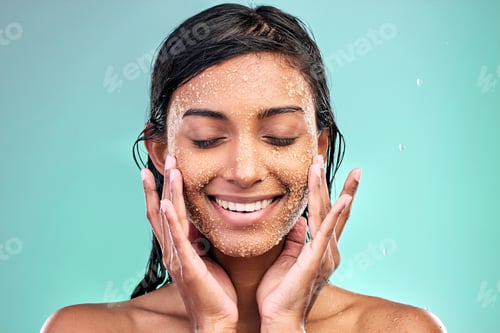 Preview: Shot of a young woman washing her face with a product against a blue background