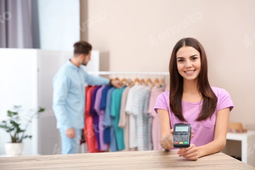 Preview: Female shop assistant with payment terminal at counter. Space for text