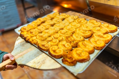 Preview: Baker removing baked puff pastry palms from the oven
