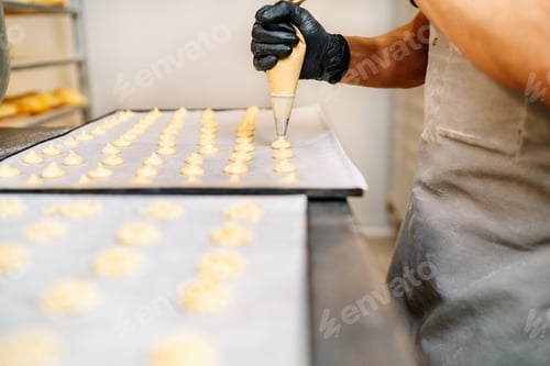 Preview: hands of a Pastry Chef with confectionary bag squeezing cream in the pastry shop bakery