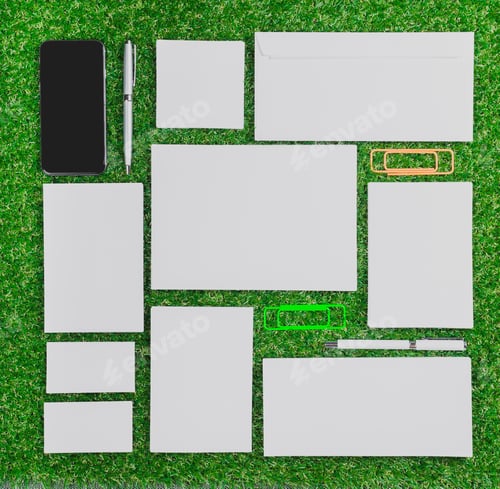 Preview: Assorted stationery items arranged on green grass in a creative layout under natural light