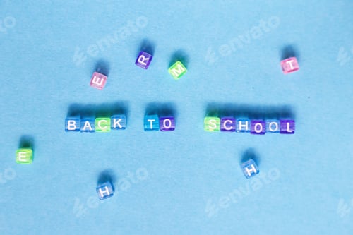 Preview: The inscription back to school made by multicolor plastic cubes on a blue background.