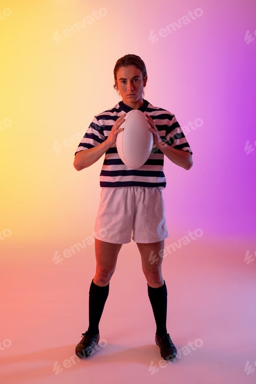 Preview: Portrait of caucasian female rugby player with rugby ball over neon pink lighting