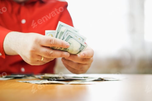 Preview: closeup of male hands counting a stack of US one hundred dollar bills
