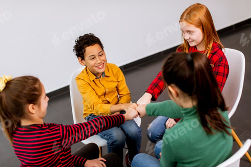 Preview: Portrait of cute little kids in jeans talking and sitting in chairs against white wall
