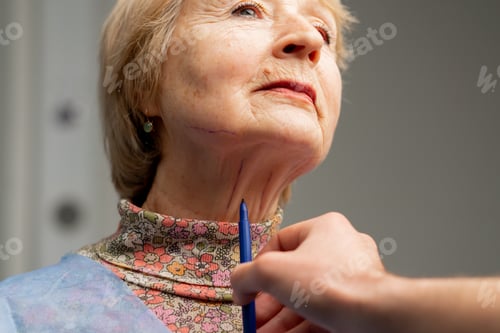 Preview: plastic surgery clinic a doctor makes markings on the face of an elderly woman before a facelift