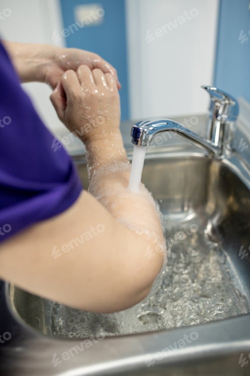 Preview: Young female doctor, assistant, nurse or surgeon washing hands and wrists