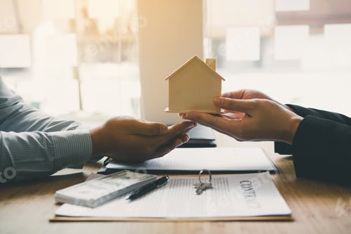 Preview: Real estate agent congratulations to new buyer by giving house model to client in the agency office.