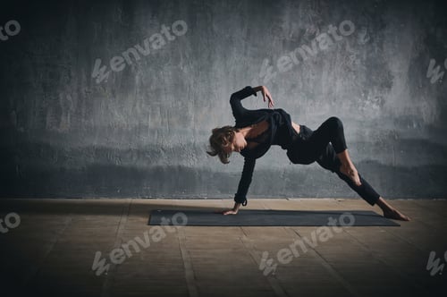 Preview: Beautiful sporty fit yogini woman practices yoga asana Wild Thing Pose in the dark hall