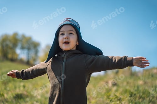 Preview: Girl with outstretched arms in pilot suit plays outdoors