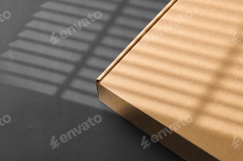 Preview: A cardboard box casting shadows on a dark surface in a striped light pattern