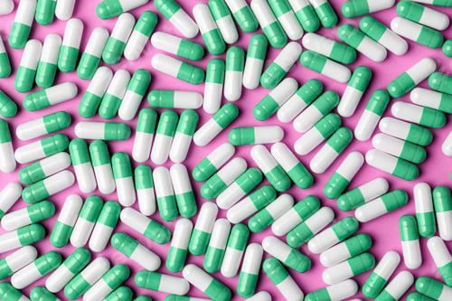 Preview: Green and white capsules cover bright pink background, clean medical pattern for pharmacy branding
