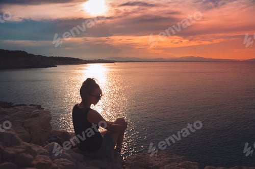 Preview: Silhouette of a girl standing on the beach enjoy freedom at the beach at sunset. Vacation concept.