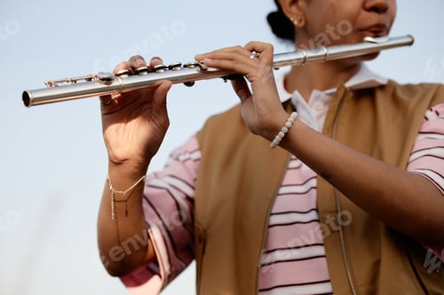 Preview: Young Adult Woman Performing Melodic Tune on Silver Flute Outdoors