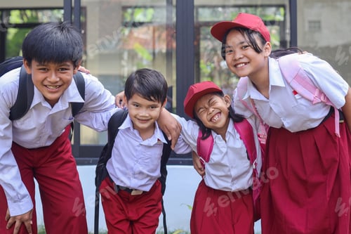 Preview: Happy cute school children in uniform standing in row with holding each other and smiling