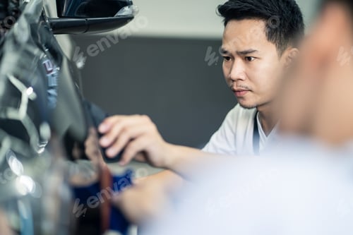 Preview: Asian car film protection male worker installing film to black color car in garage