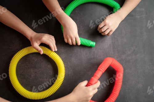 Preview: anti stress sensory pop tube toys in a kids hands. kids hands plays with poptube toy on black table