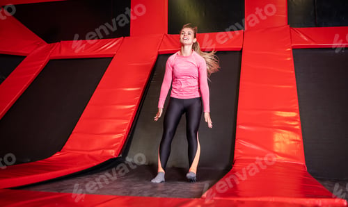 Preview: Fit young woman jumping on trampoline in fitness gym