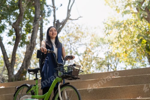 Preview: Smiling Asian woman with bicycle outdoors. Concept of eco friendly commuting