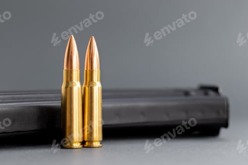 Preview: Two bullets against Kalashnikov assault rifle clip, magazine on blurred gray background