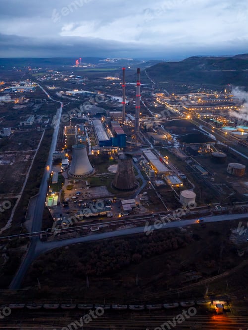 Preview: View of a heavily smoking factory at night, industrial area aerial view
