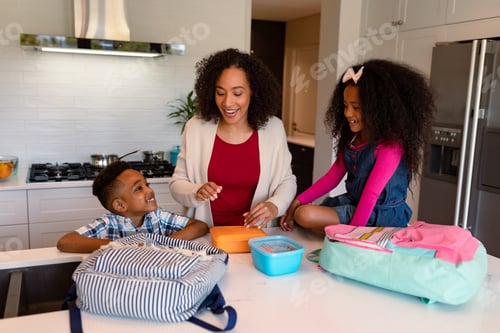 Preview: Happy african american mother and children preparing lunchboxes for school