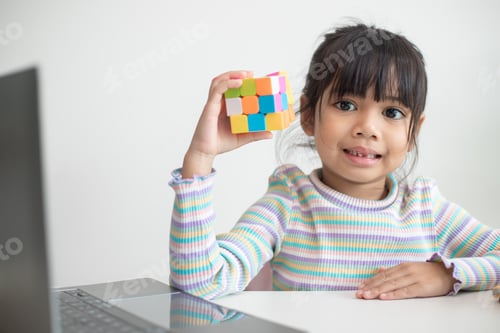 Preview: Asian little cute girl holding Rubik's cube in her hands. Rubik's cube is a game that increases the