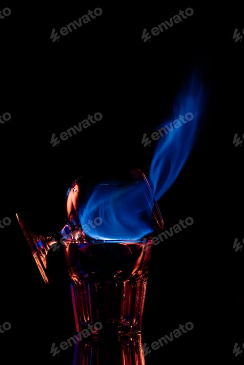 Preview: close up view of alcohol sambuca drink burning in glass on black background