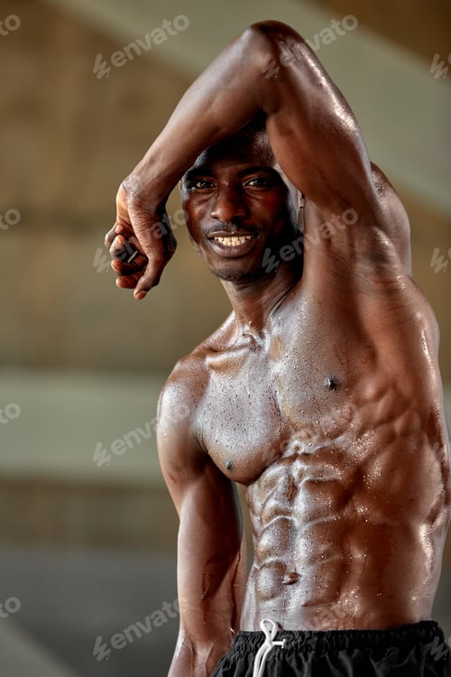 Preview: Handsome afro American sportman standing on the street while taking break after training. Black male
