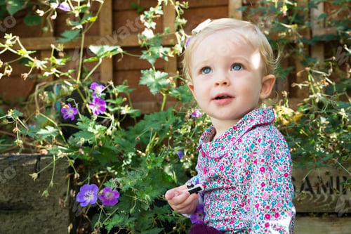 Preview: Blue eyed baby girl looking up in garden