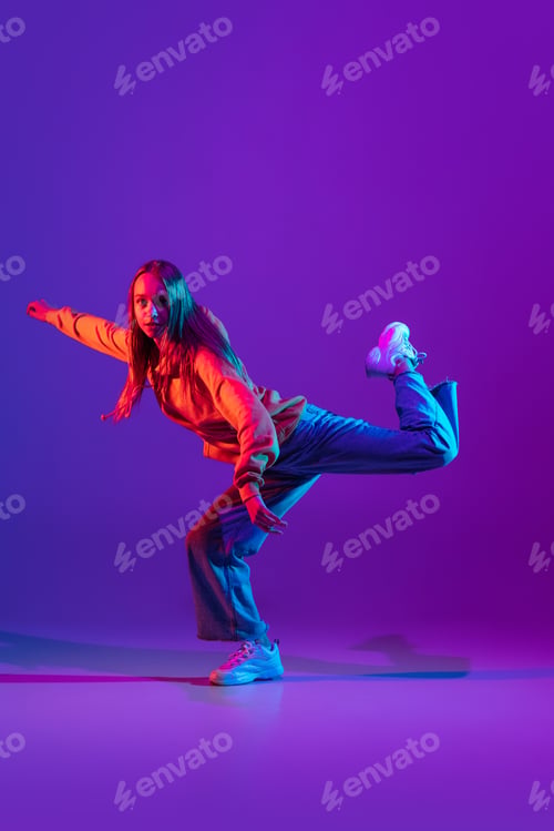 Preview: Stylish sportive girl dancing hip-hop in stylish clothes on colorful background at dance hall in