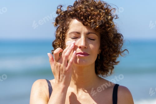 Preview: Sensual woman applying sunscreen on face