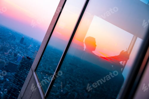 Preview: Reflection of a man taking a selfie in high tower city view sunset city