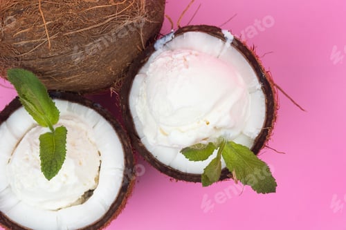Preview: Vanilla ice cream balls in fresh coconut halves decorated with mint leaves on a pink background
