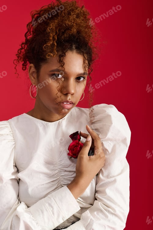 Preview: Young woman in stylish outfit poses confidently against a vibrant red background