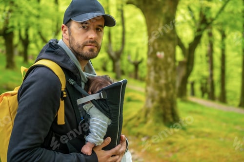 Preview: A young father with a yellow backpack walking with the newborn child in the backpack