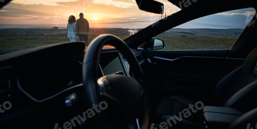Preview: View from car of young couple looking at beautiful sunset.