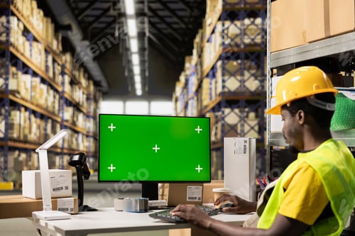 Preview: Black worker overseeing e-commerce operations on pc next to mockup
