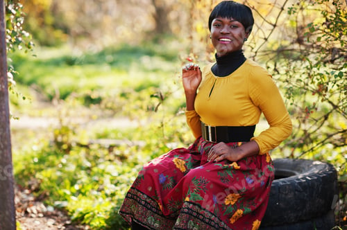 Preview: African american girl at yellow and red dress at golden autumn fall park.
