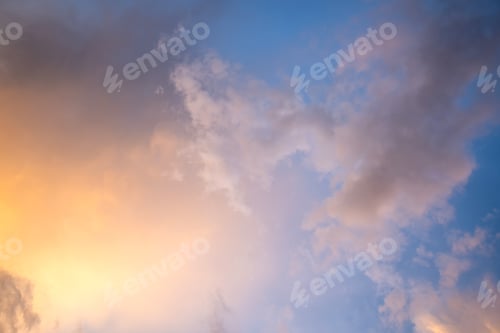 Preview: Dramatic sunset landscape with puffy clouds lit by orange setting sun and blue sky