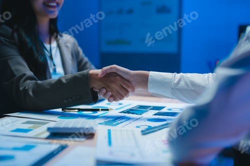 Preview: Businesswomen shaking hands after successful meeting over financial charts