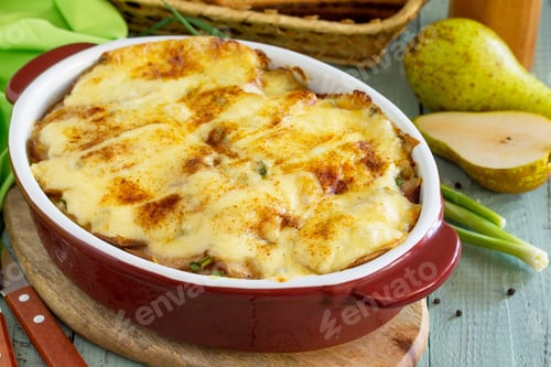 Preview: Potato gratin with pear, raclette cheese, and bacon on rustic wooden table.