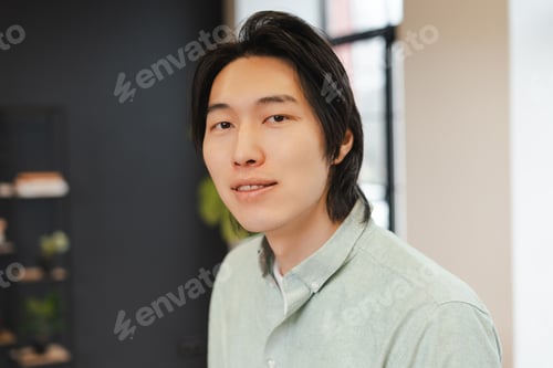 Preview: Handsome asian man in business casual shirt looking at camera working in modern office
