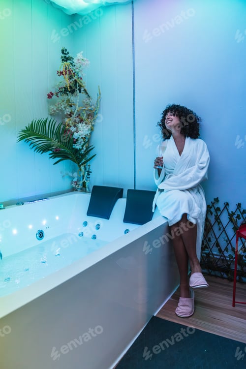 Preview: Beautician smiling and relaxing in modern spa center with hydromassage tub